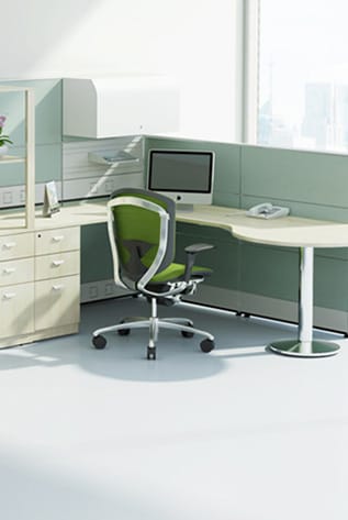 Office space with low partitioning screens, desk, computer, and green office chair.