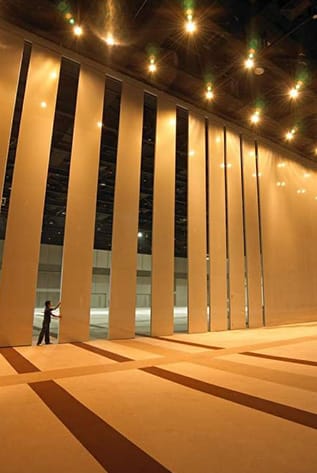 Person adjusting movable walls in a large, brightly lit space.