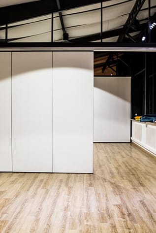 Modern office interior featuring white movable walls and wood flooring.