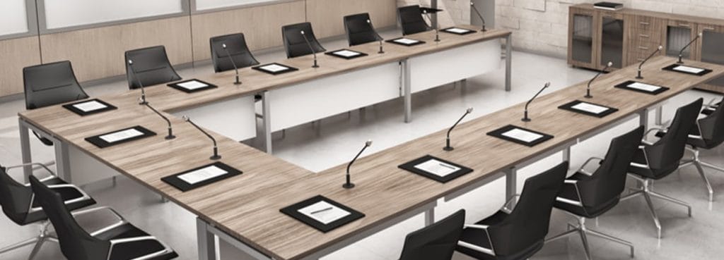 I-Work Conference table with black chairs, microphones, and wood-look desktop in a U-shape arrangement.