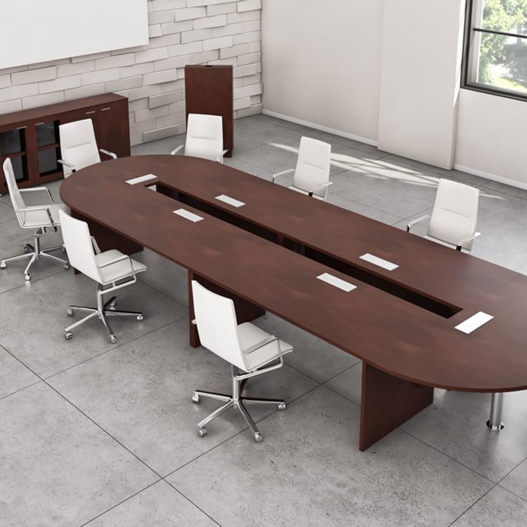 Manager Conference Room with a spacious oval wooden table, seven modern white office chairs on wheels, sleek gray tiled floors, an exposed brick accent wall, and large windows that fill the space with natural light. Studio Office Cyprus