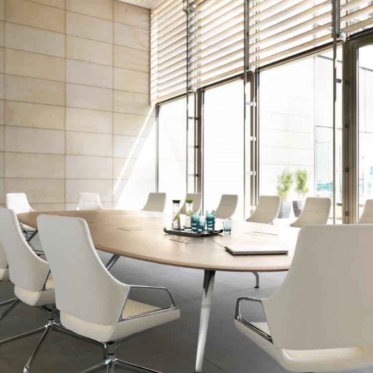 Modern conference room featuring Wilkhahn Graph chairs in white leather around an oval table.
