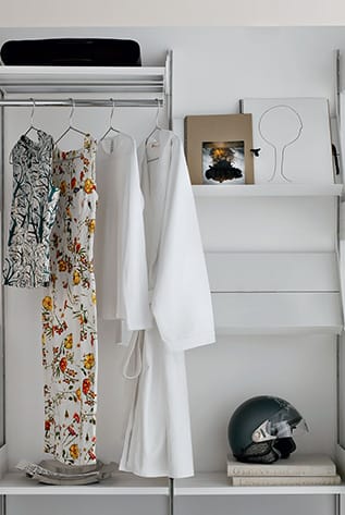 White modular closet system with clothes, books, and helmet. Stylish, customizable storage.