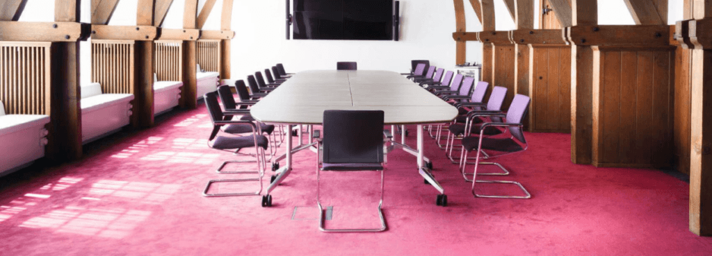 Conference room featuring a Confair Folding Table with chairs on a pink carpet.