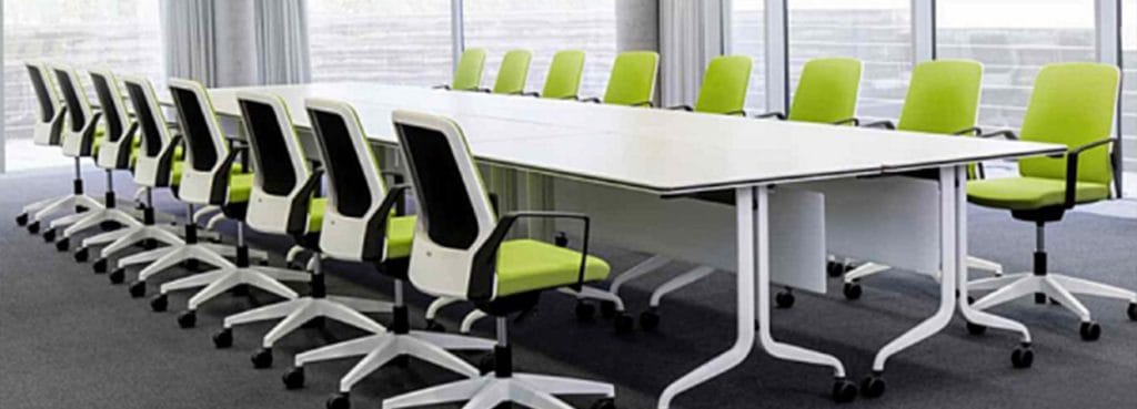Conference room featuring Interstuhl BUDDYis3 chairs in green and white, arranged around a large white table.