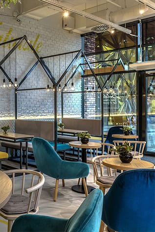 Modern Cafeterias with teal velvet chairs, wood tables, and black metal accents.