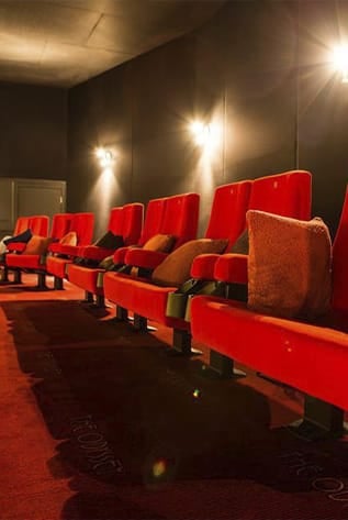 Red plush Cinema seating with lumbar support, cup holders, and reclining options for ultimate comfort.