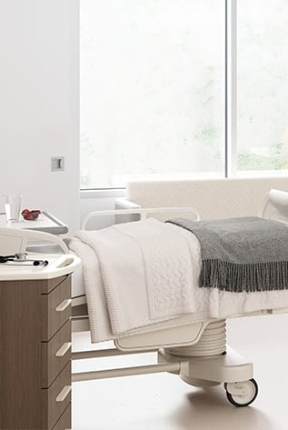 Modern healthcare furniture: adjustable bed with side table in a bright, clean room.