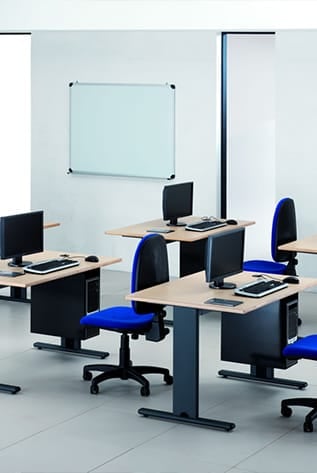 Modern Higher Education classroom. Light wood desks, blue chairs, and black computer towers.