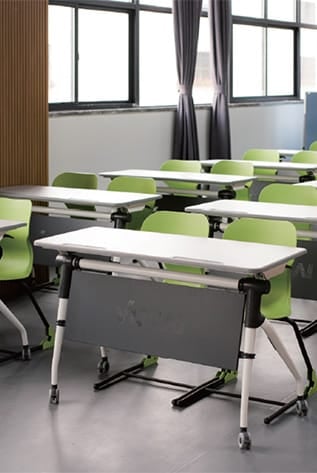 Classroom with modern, functional furniture for Higher Education. White tables, green chairs.