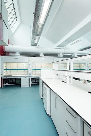Bright, clean laboratory featuring white Laboratory Furniture and blue flooring.