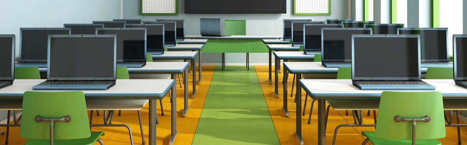 Classroom with laptops for higher education. Modern desks and green chairs.