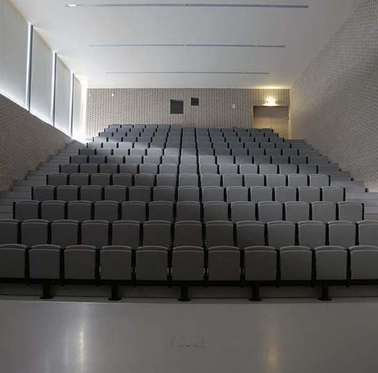 Indoor Amphitheater seating with gray chairs in tiered rows.
