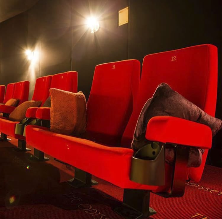 Comfortable red Cinema seating with cup holders and pillows, perfect for an immersive movie experience.