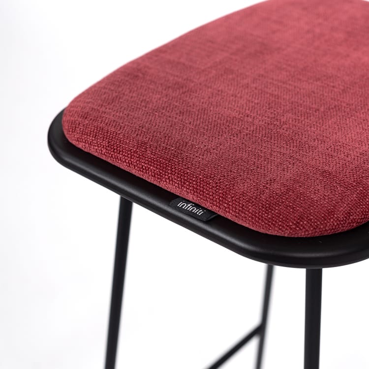Close-up of Klejn Stool with a red fabric seat and black metal frame, showcasing its modern design.