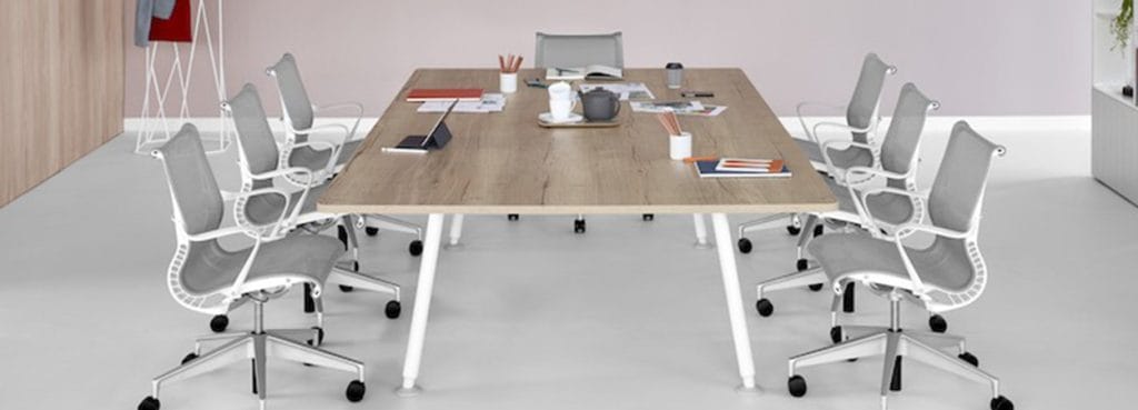 Locale Conference Table with light wood top and white legs, surrounded by gray office chairs.