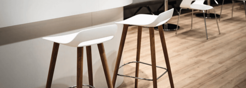 Modern Occo Stool by Wilkhahn. White ergonomic seat with wooden legs and a chrome footrest.