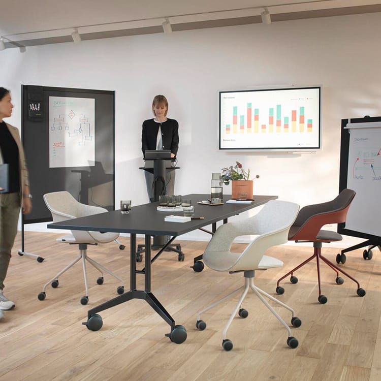 Modern meeting space with a black Occo Conference Table, rolling chairs, and presentation boards.