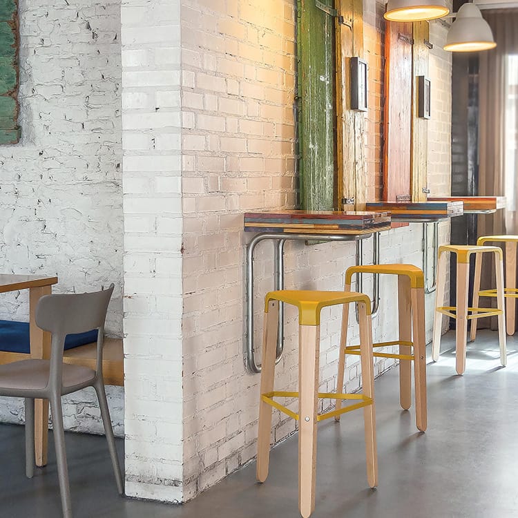 Yellow Picapau Stool with wooden legs. Modern seating for social spaces.
