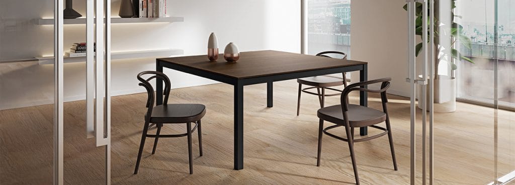 Modern Zefiros X desk with a wood top and black frame, surrounded by stylish wood chairs.