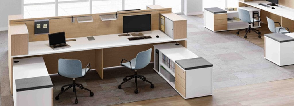 Modern office featuring the Atlante workstation system. White desks, wood panels, and light blue chairs.