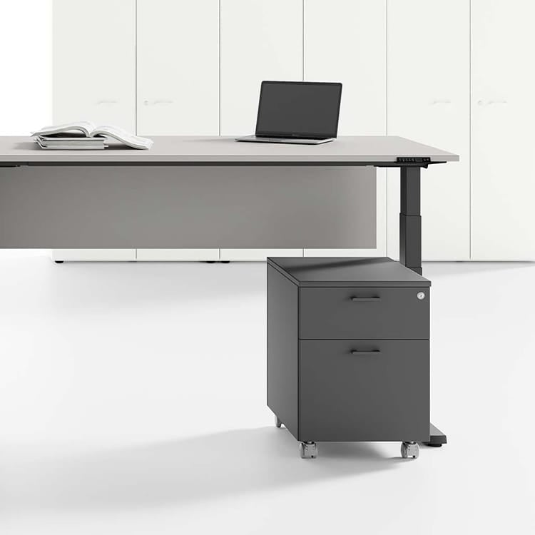 Modern gray UP desk with file cabinet, laptop, and book in a bright office space.