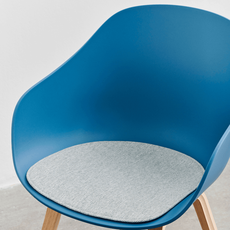 Close-up of HAY AAC 222 chair in blue with a gray seat cushion and wooden legs. Modern style.
