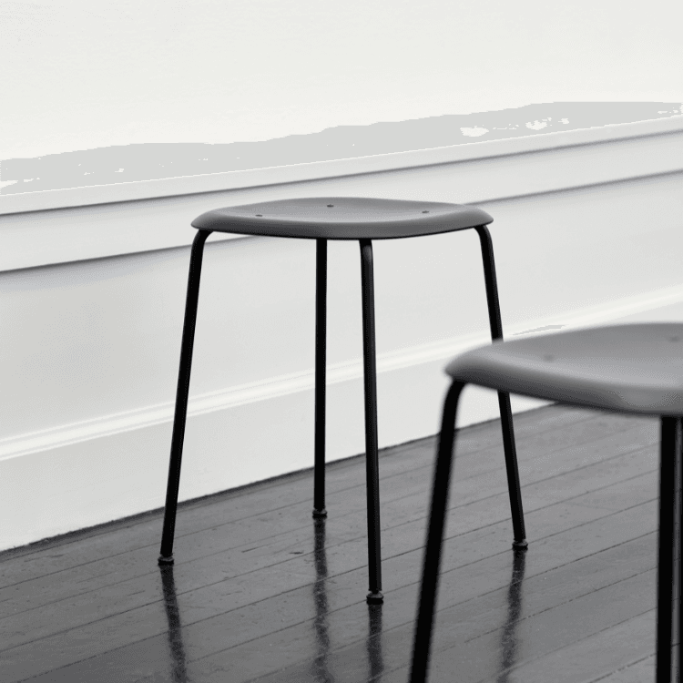 HAY Soft Edge 75 stool. Minimalist design with a gray plastic seat and black steel legs. Stackable stool for modern spaces.