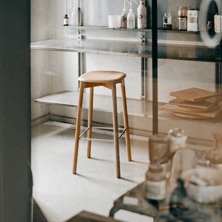 HAY Soft Edge 82 stool. Minimalist design with wooden seat, legs, and metal footrest. Ideal seating for modern spaces.
