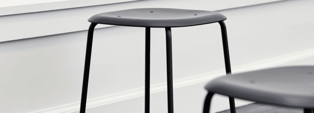HAY Soft Edge 75 stool. Modern design with a gray plastic seat and black steel legs. Stackable.