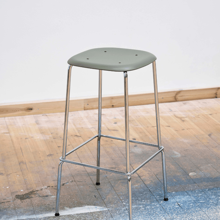 HAY Soft Edge 85 stool. Minimalist design with a green plastic seat and steel legs.