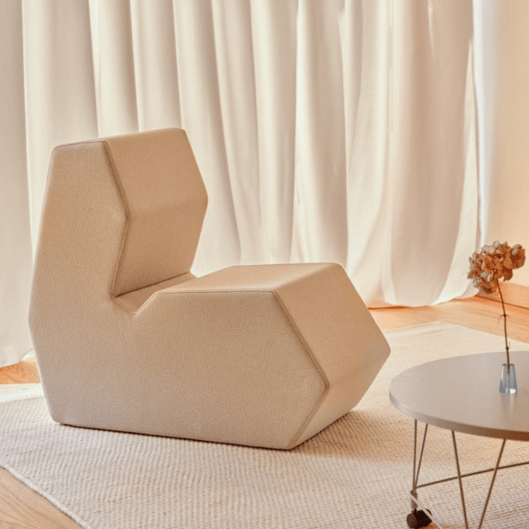 Angled view of a beige Shape pouf with a backrest, ideal for social spaces.