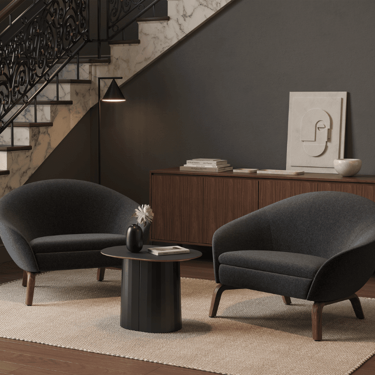 Two gray Ever Lounge Chair with a round table on a rug in front of stairs.