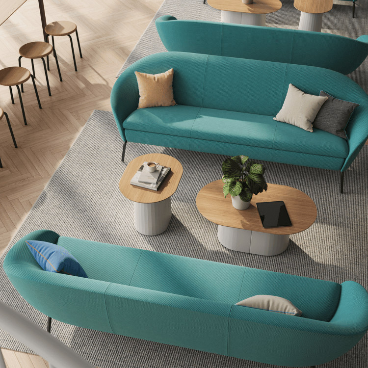 Overhead shot of NaughtOne Ever Sofa in teal, featuring soft curves, pillows, and tables on a gray rug.