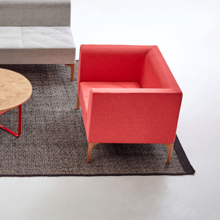 Modern red Hatch Lounge Chair with wood legs on a textured rug.