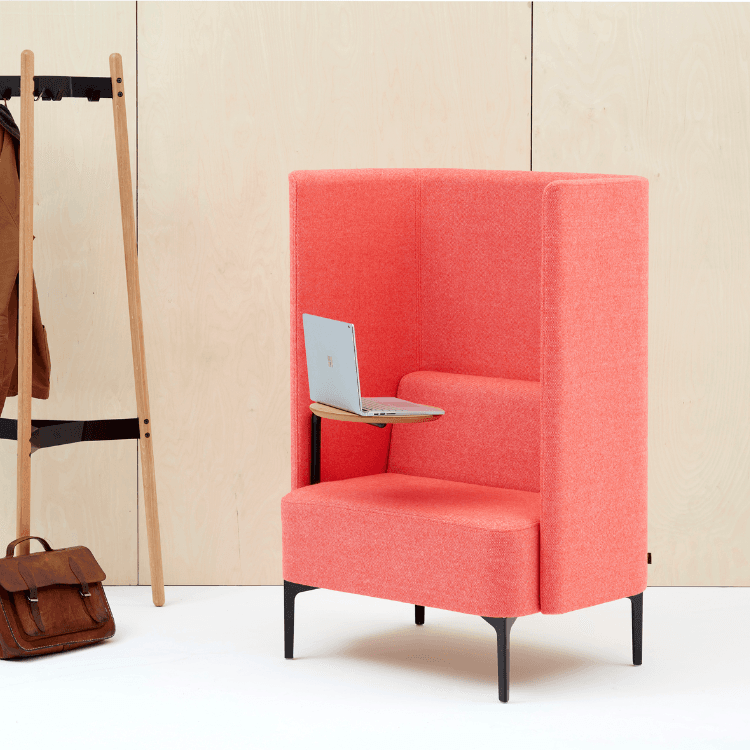 Coral Pullman Chair with tablet desk, laptop, and black legs. Acoustic privacy seating for open spaces.