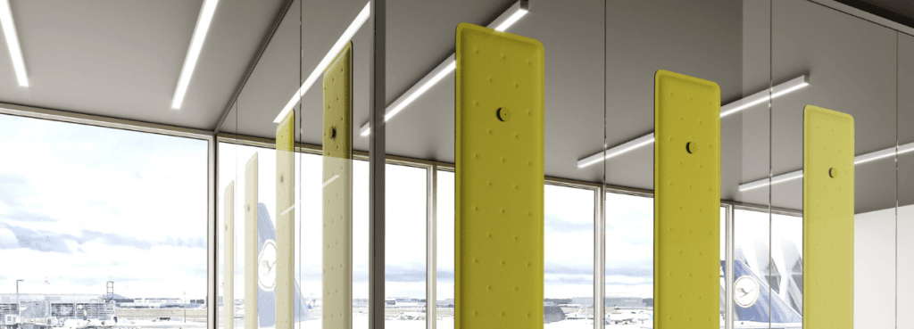 Angled view of yellow Zen Soundshaper Acoustic Panels by Steelbox. Modern modular design for sound comfort. Airport background.