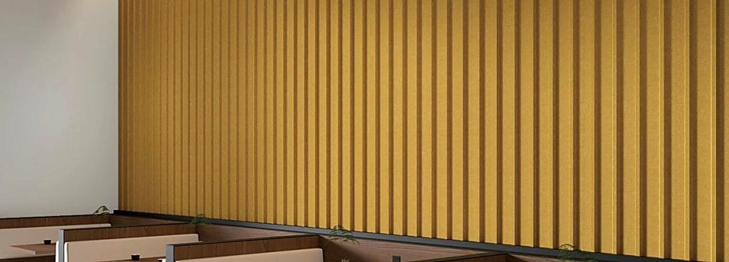 Акустическая панель 3D в форме U-образного канала горчично-желтого цвета с глубокими вертикальными рифлеными ребрами, установленная на стене над сиденьями кабины.