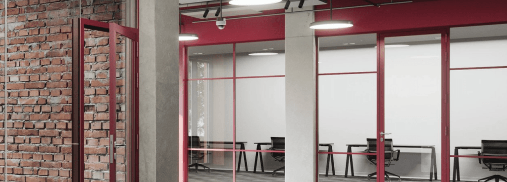 Silence Fire-Resistant System frames define this modern workspace with red metallic trim and exposed industrial brick.