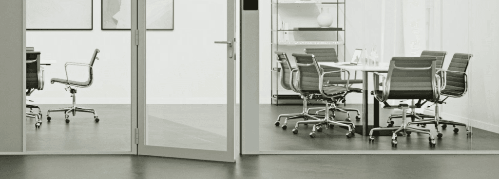 Interior view of an office featuring the Silence System partition with a glass door opening into a meeting room.