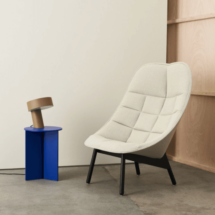 Uchiwa armchair in cream fabric with a black base, featuring a curved, fan-inspired silhouette in a modern interior.