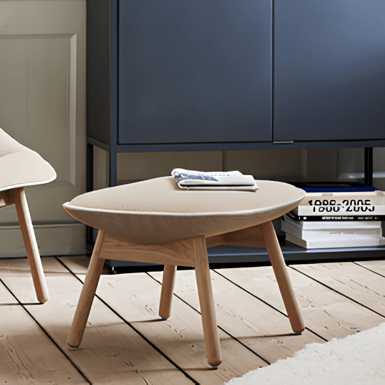 Minimalist HAY Uchiwa Ottoman featuring a beige cushioned top and light oak legs situated in a modern living space.