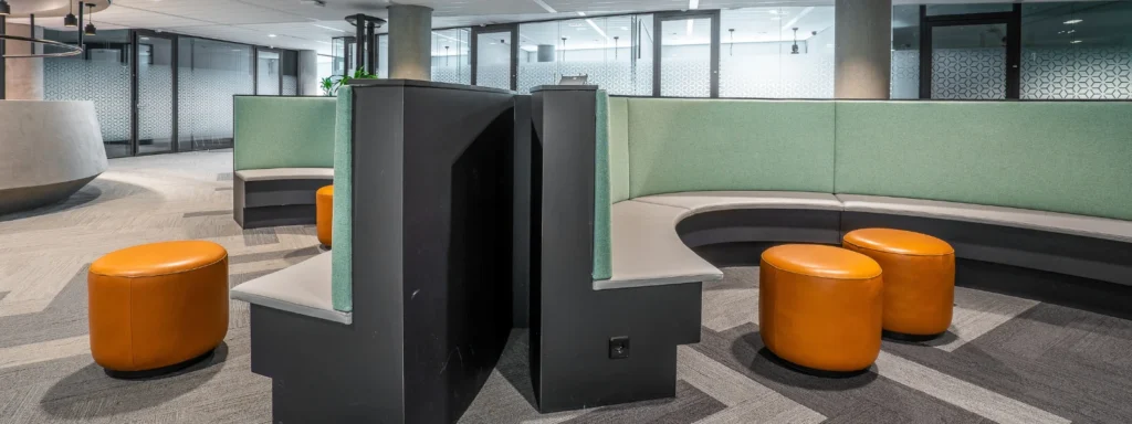Curved office seating with green acoustic panels and orange stools for choosing the right acoustic panels.