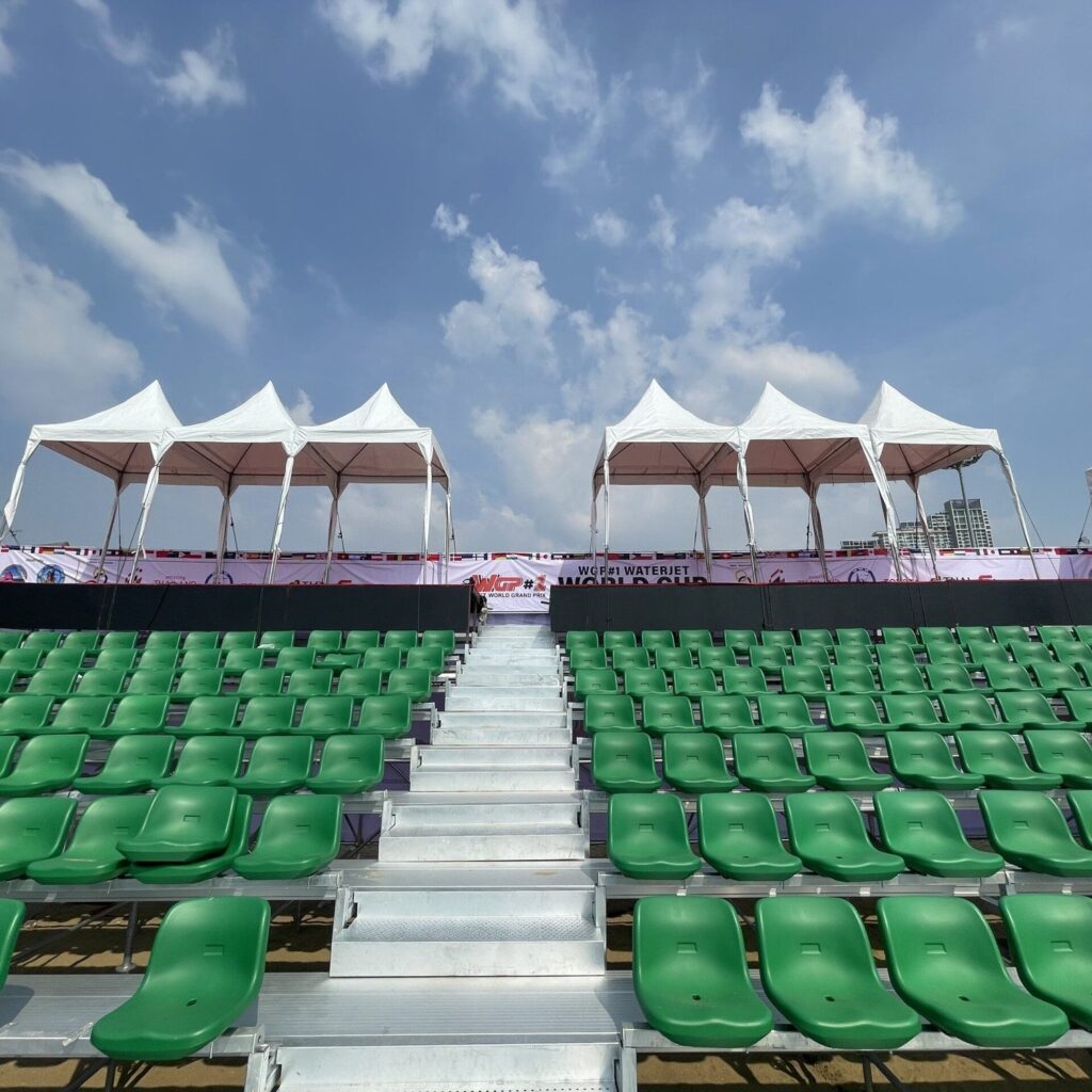 Outdoor grandstand with green seats either side of a steel aisle