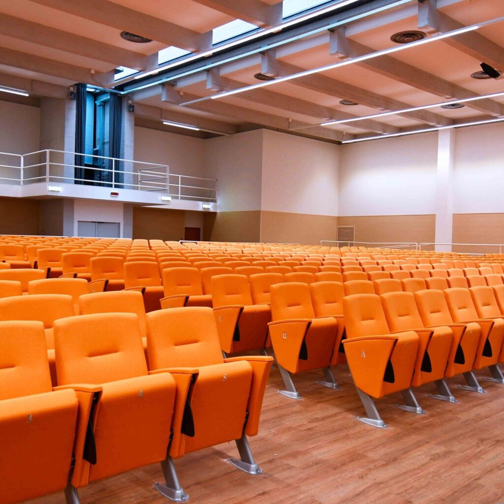 Orange Eidos seats on beams in a large hall