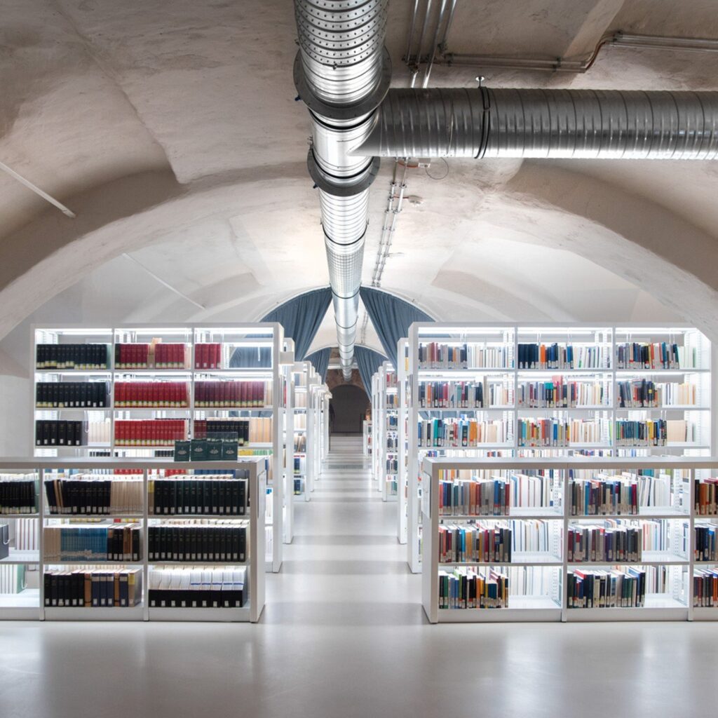 Tube-frame library shelving under a vaulted ceiling